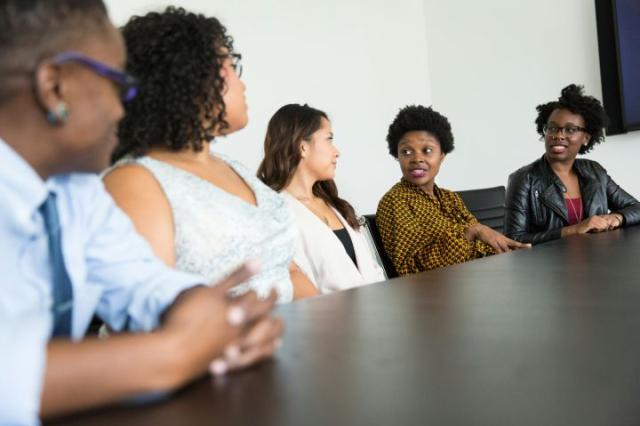 5 diverse people sitting at a table talking. Photo by Christina @ wocintechchat on Unsplash